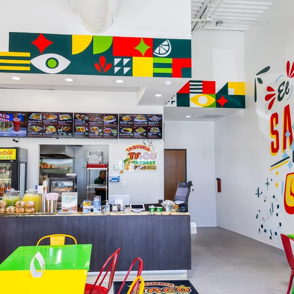 Colorful interior of Taqueria Taco Express with menu boards, a counter, and vibrant murals.