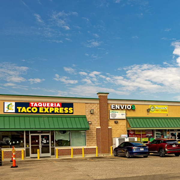 Exterior of Taqueria Taco Express with a green awning, yellow sign, and parked cars.