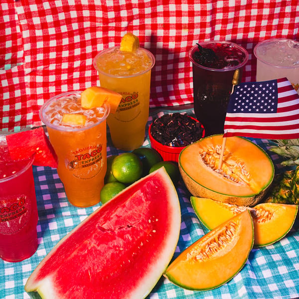 Assorted Taqueria Taco Express drinks with watermelon, cantaloupe, limes, and a small American flag.