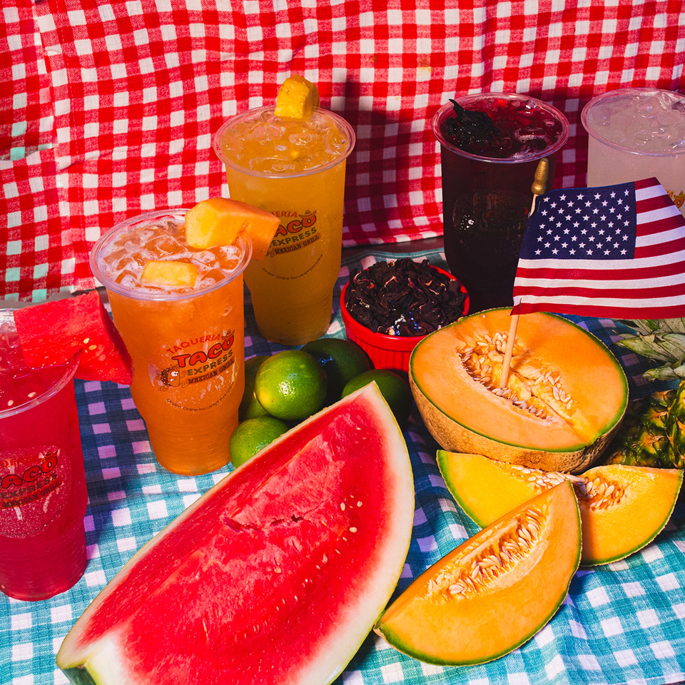Assorted Taqueria Taco Express drinks with watermelon, cantaloupe, limes, and a small American flag.