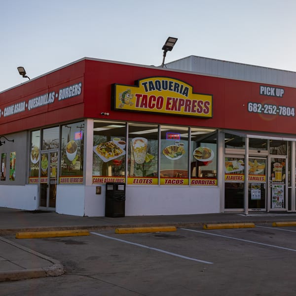 Exterior of Taqueria Taco Express, a red building with a yellow sign and food images on the windows.