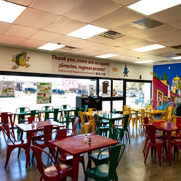 Colorful red, green, and yellow tables and chairs fill the bright dining area of Taqueria Taco Express.