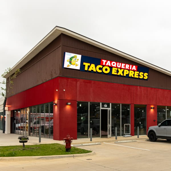 Exterior of Taqueria Taco Express, a red and brown building with a large sign and glass windows.