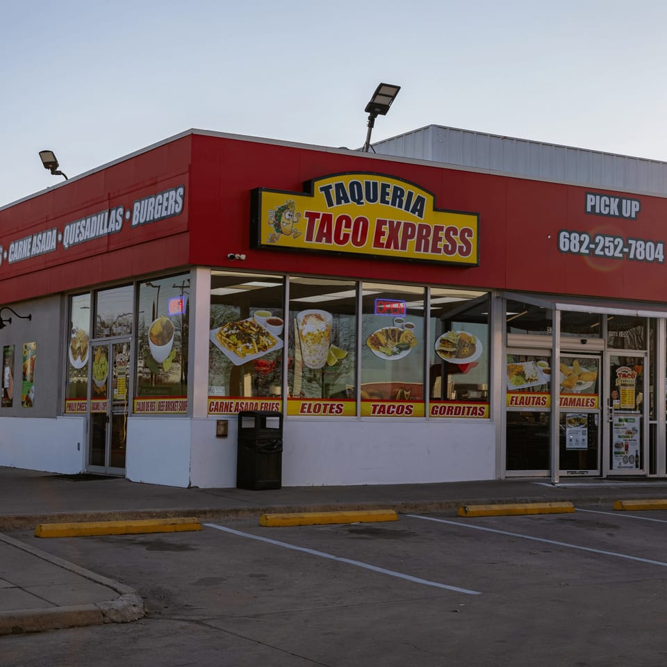 Exterior of Taqueria Taco Express, a red building with a yellow sign and food images on windows.